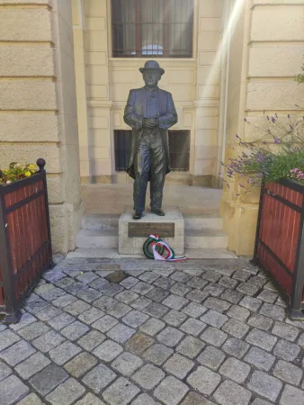 Bronzszobor talapzaton egy épület mellett Sopronban