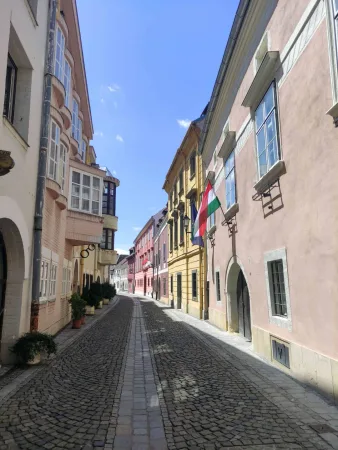 Üres kövezett utca színes történelmi házak között Sopronban