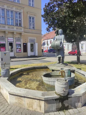 Szökőkút hordót vivő férfi bronzszobrával Sopronban
