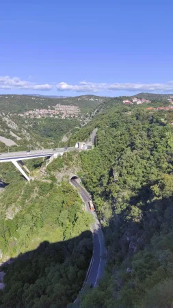Most a tunel vedoucí silnicí skrz zalesněný kaňon u Rijeky