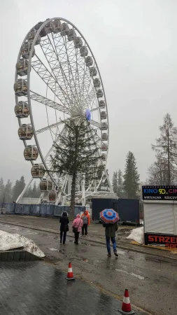 Velké kolo a lidé s deštníky při deštivém počasí v Zakopaném
