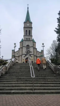 Dvojice lidí stoupá po schodišti ke kostelu v Zakopaném