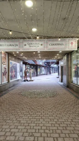 Pasáž s osvětlenými řetězy a tabulí Góralska Tradycja v Zakopaném