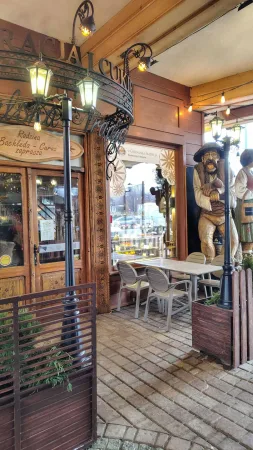 Vstup do restaurace s kovanými lucernami a dřevěnou sochou v Zakopaném
