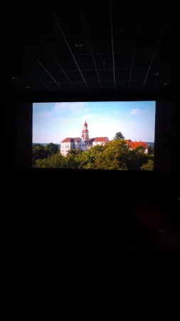 Záběr zámku na filmovém plátně v temném kinosále během projekce
