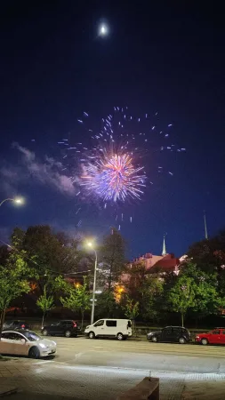 Barevný ohňostroj vybuchuje na nočním nebi nad siluetou města.
