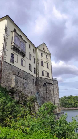Bílá fasáda zámku Orlík s okny a balkonem