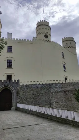 Pohled zdola na hranolovou věž zámku Orlík s cimbuřím a hodinami