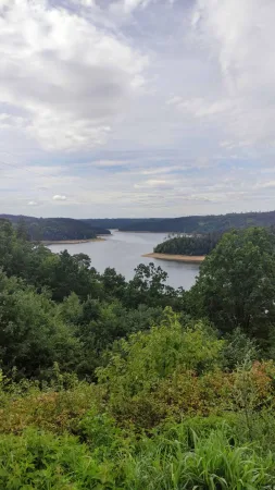 Výhled na klikatící se Orlickou přehradu mezi zalesněnými kopci od Žďákovského mostu