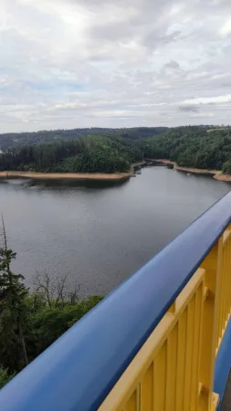 Pohled z lávky Žďákovského mostu na Orlickou přehradu s obloukovou konstrukcí v dálce