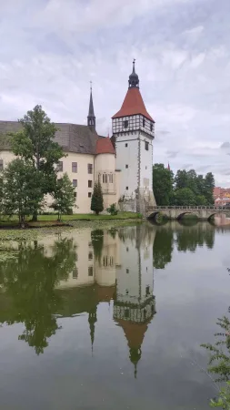 Zámek Blatná s charakteristickou věží odrážející se v hladině vodního příkopu