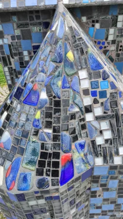 Detailní záběr na modrou skleněnou mozaiku zdobící miniaturu hradu v parku
