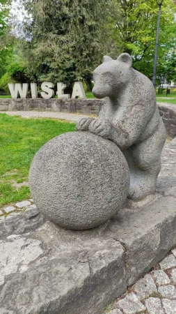 Detailní záběr na kamennou sochu medvěda tlačící velkou žulovou kouli v parku