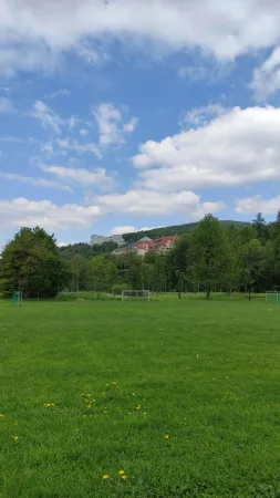 Fotbalové hřiště s výhledem na hotel a zalesněné kopce Beskyd