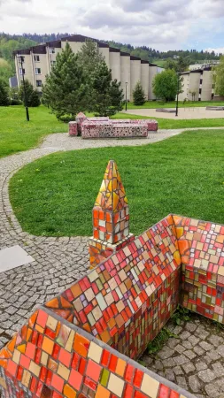 Oranžová mozaiková miniatura hradu na pozadí panelových domů ve Wisle