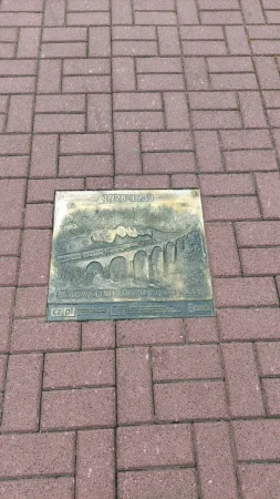 Bronzová pamětní deska připomínající výstavbu železniční trati v letech 1928 až 1983