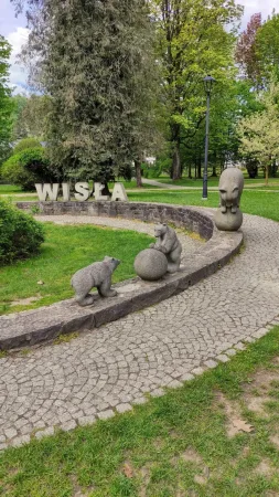 Skupina kamenných soch medvídků hrajících si u nápisu WISŁA v parku