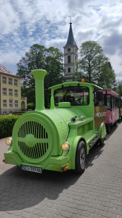 Zelený turistický vláček s vagóny projíždí centrem Wisly kolem kostelní věže