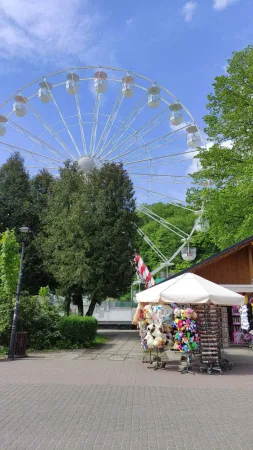 Bílé vyhlídkové kolo ve Wisle vykukující nad zelenými korunami stromů