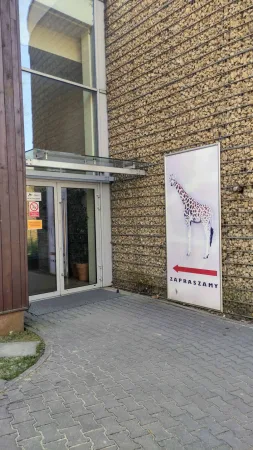 Vchod do pavilonu žiraf s velkým plakátem žirafy v krakovské zoo
